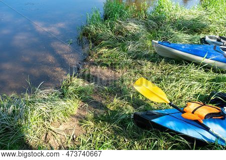 Tourist Canoes With Paddles Stand On The River Coast In Summer On A Water Hike. Rafting On Inflatabl