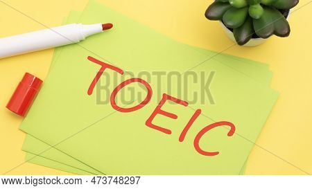 Paper With Text Toeic On A Yellow Background With Stationery