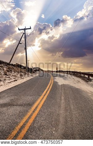 Sunlight Through The Storm Clouds Over Roadway Along Chapin Beach In Cape Cod, Massachusetts.