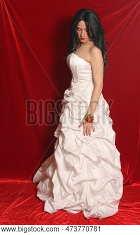 Woman Wearing Satin Corset Style Ball Gown Wedding Dress On Red Velvet Background