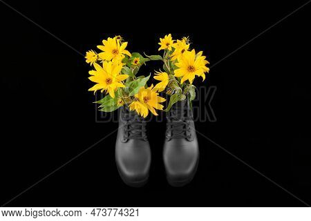 Black Women Platform Boots With Bouquet Of Yellow Jerusalem Artichoke Flowers, Black Background. Bea