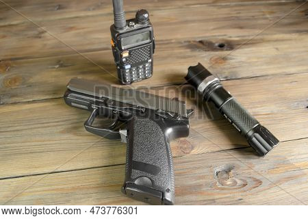 A Walkie-talkie, A Gun And A Flashlight On A Wooden Table. Weapons And Military Equipment. Devices F
