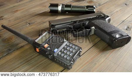 A Walkie-talkie, A Gun And A Flashlight On A Wooden Table. Weapons And Military Equipment. Devices F
