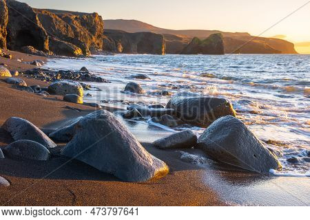 Scenic Beach With Black Sand By Low Tide At Sunset, Sharp Mountain Volcanic Cliffs On Atlantic Ocean
