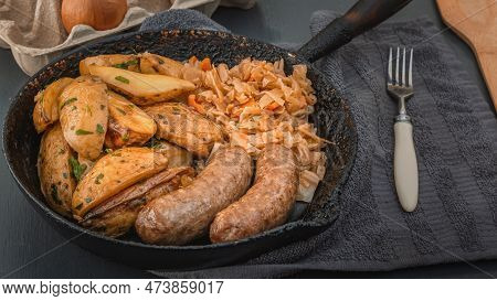Grilled Sausages, Baked Potato Wedges And Stewed Cabbage Cooked In An Old Cast Iron Skillet. Close-u