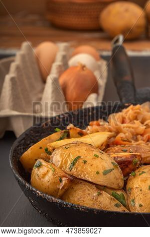 Baked Potato Wedges And Braised Cabbage Cooked In An Old Cast Iron Skillet. Close-up