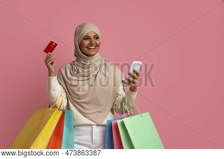 Smiling Islamic Lady Wearing Hijab Holding Smartphone, Creadit Card And Shopping Bags