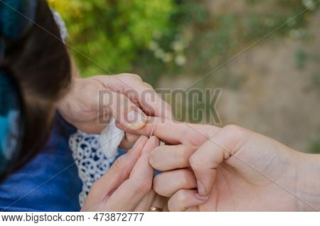 A Splinter In A Child's Hand. The Woman Is Trying To Pull The Splinter Out Of The Child's Hand.