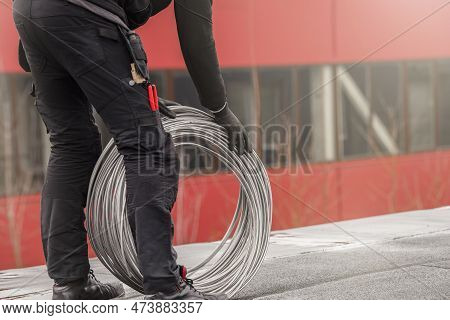 Ground Wire. A Worker Lays A Ground Cable On The Roof Of A Building. Electrician Fixing Aluminum Wir