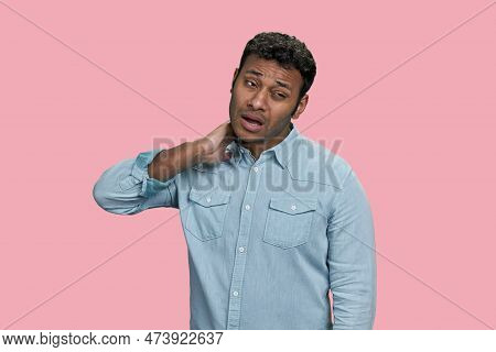 Portrait Of Indian Man Suffering From Neckache. Isolated On Pink Background.