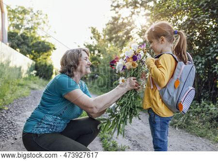 Cute Granddaughter Hugging Her Happy Grandmother. The Hugs Of An Elderly Woman And A Little Girl Aga
