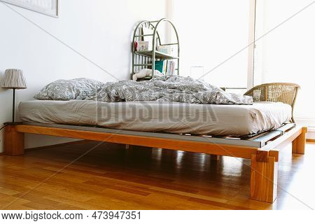 Unmade Blanket On Bed In Bedroom With Large Bright Window, Sunbeam. Interior Of A Bedroom With A Bed