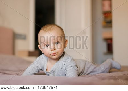 Small Baby Boy Lying On Stomach And Raising His Head While Looking Surprised, Newborn