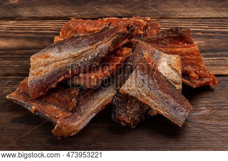 Pieces Of Cleaned Dried Fish On Wooden Background. Dry Peppered Pollack. Amber With Pepper.