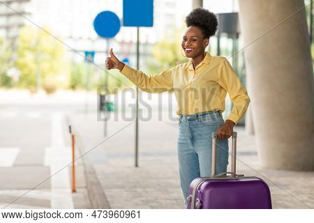 African Female With Suitcase Catching Cab Standing In Urban Area