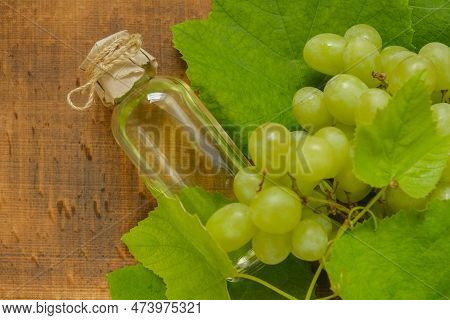 Grape Oil On Wooden Background.oil Bottle And Bunch Of Green Grapes.base Cosmetic Oil For Massage An