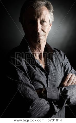 Faible coup de clé d'un beau homme Senior sur fond sombre
