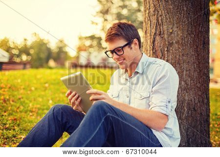 education, technology and internet concept - smiling male student in eyeglasses with tablet pc outside