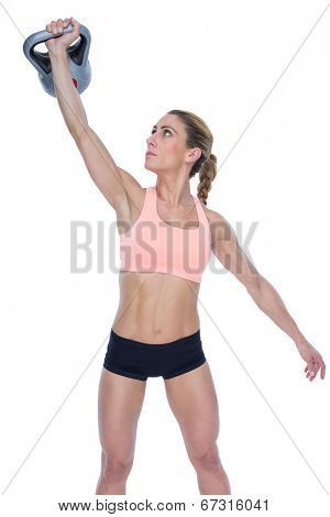 Female crossfitter lifting up kettlebell on white background