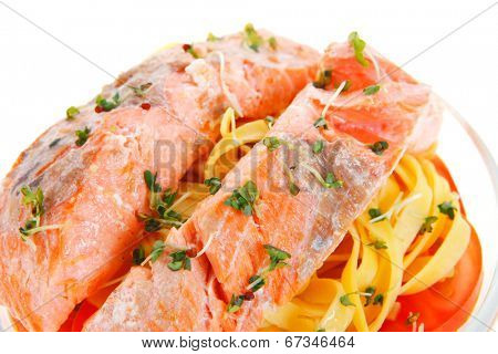 fresh fried natural pink salmon on italian traditional tagliatelle backed with tomato and vegetables isolated over white background