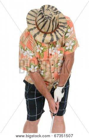 Closeup of an eclecticly dressed male tourist standing over a golf ball preparing to take his turn. He is wearing a Hawaiian shirt, striped shorts and a zebra stripe hat that hides his face.