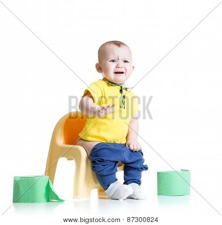 crying child sitting on chamber pot with toilet paper