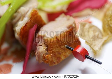 Closeup of a skewer of pork jowls.