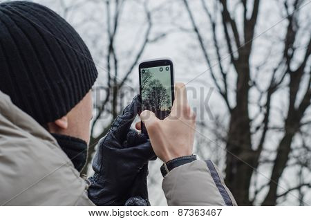 Man Tourist Taking Photos Of A Tree With Mobile Phone