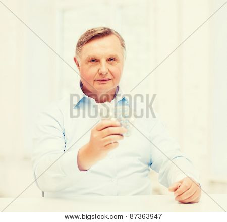 healthcare, madicine, pharmacy and elderly concept - old man with pack of pills