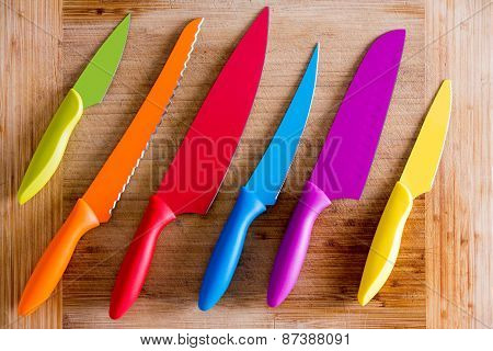 Colorful Kitchen Knives On Wooden Cutting Board