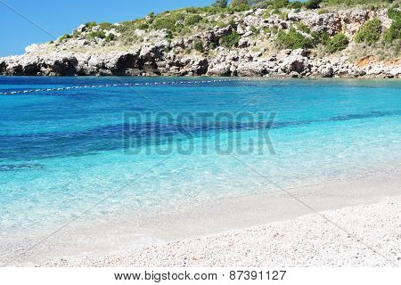 Blue clear water on the beach with a rock