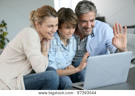 Happy family of three waving at camera during video call