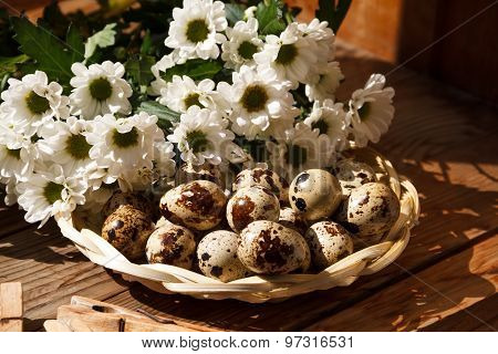 Quail Eggs In A Basket And Flowers.