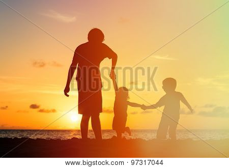 father and two kids walking at sunset