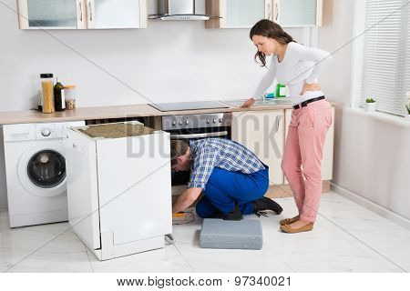 Woman Looking At The Repairman Repairing Dishwasher