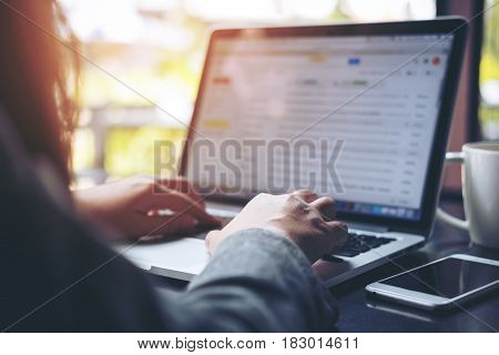 A business woman working and typing on laptop keyboard with mobile phone on table and blur nature background