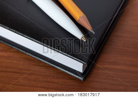 Black Diary, Or Sketchbook With Pen And Pencil On Th Table