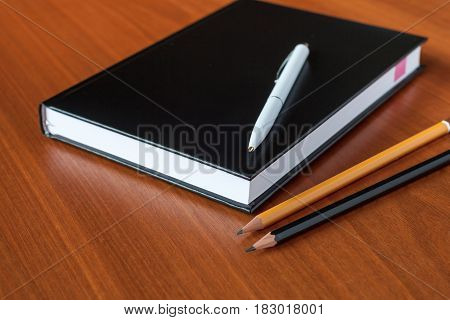 Black Diary, Or Sketchbook With Pen And Pencil On Th Table