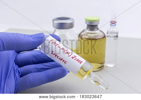 Scientist with blue latex gloves holds vials of ZIKA virus in laboratory for analysis