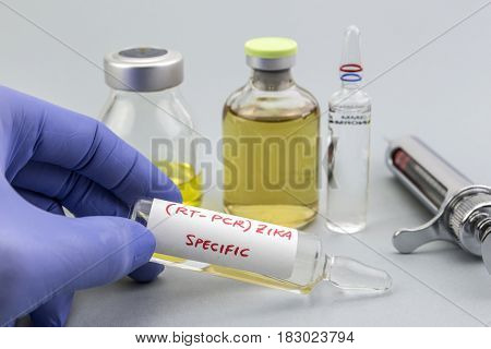 Scientist with blue latex gloves holds vials of ZIKA virus in laboratory for analysis