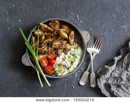 Crispy za'atar fries with garlic scallion sauce in a frying pan on a dark background