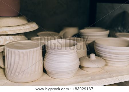 Handcrafted pottery on wooden shelf, ceramic handmade crockery in pottery workshop or studio