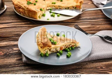 Piece of tasty chicken pot pie with green peas on plate