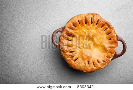 Delicious chicken pot pie in saucepan on grey table