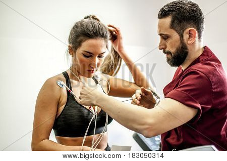 doctor visiting and monitoring a young girl during exercise with electrocardiogram