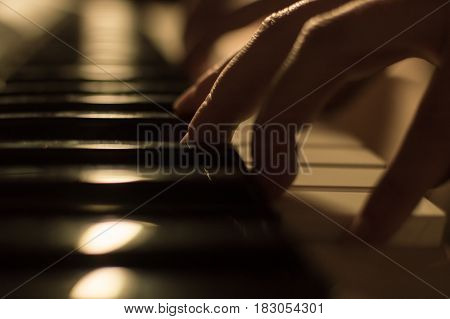 Closeup soft focused atmospheric photography of a hand playing the piano keys. Concept: Music creating, composing, lyrics, performance