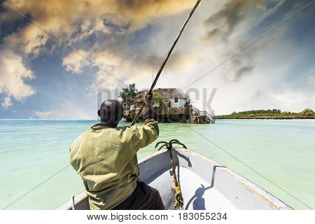 arfican on the boat sailing to the Rock restaurant in ocean on the horizon, Zanzibar