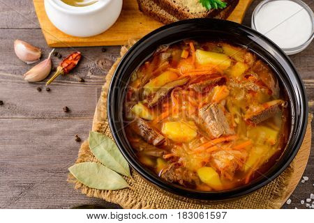 Shchi - traditional russian cabbage soup on wooden table. Rustic style. Selective focus.