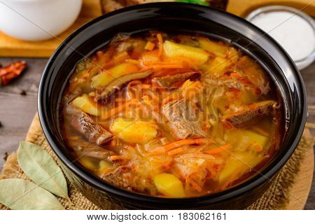 Shchi - traditional russian cabbage soup on wooden table. Rustic style. Selective focus.