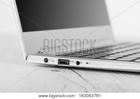 Detail on HDMI connector card slot Ultra-thin notebook. The silver notebook on the desk the open notebook lies on a wooden background.